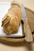 Baguette on breadboard with knife