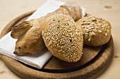 Baguette and wholemeal rolls on breadboard