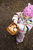 Small girl holding basket of brown eggs