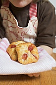 Child holding freshly baked puff pastries on cloth