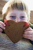 A small boy with a Christmassy gingerbread heart