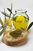 Green olive with twig on white bread, Parmesan, olive oil