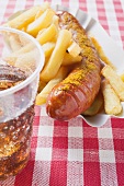 Sausage with ketchup & curry powder & chips in paper dish, cola