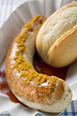 Sausage with curry powder, ketchup & bread roll in paper dish