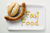 Sausage with bread roll & the word 'Fast Food' in mustard