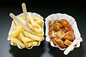 Sausage with ketchup and chips in paper dishes