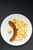 Sausage with chips and mustard on plate