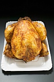 Whole roast chicken on paper plate