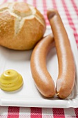 Wiener Würstchen mit Senf und Brötchen auf Pappteller