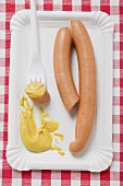 Frankfurters with mustard on paper plate