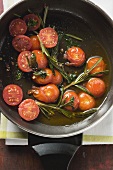 Fried cherry tomatoes with rosemary in frying pan