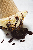 Cone of nut ice cream with chocolate sauce (upside down)