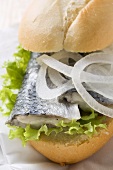 Bread roll filled with herring and onions on paper napkin