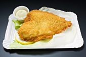 Breaded fish fillet with mayonnaise on paper plate