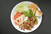 Döner meat with vegetables and flatbread on paper plate