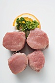 Four pork medallions, garnished with parsley and orange