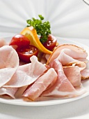 Platter of ham with cherry tomatoes, orange and parsley