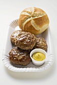 Burgers with mustard and bread roll on paper plate