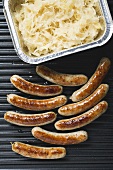 Grilled sausages from above,  sauerkraut in aluminium container
