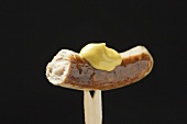 Sausage with mustard on wooden fork