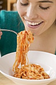 Woman eating ribbon pasta with tomato sauce