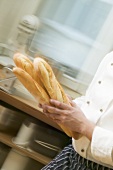 Chef hurrying through kitchen with baguettes