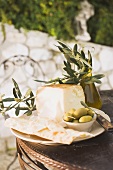 Cheese, green olives, crackers & olive oil on outdoor table