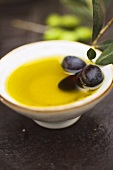 Olive oil in small bowl with black olives