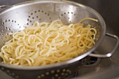 Draining cooked ribbon pasta in a colander