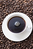 Cup of black coffee on coffee beans