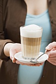 Woman holding a glass of latte macchiato