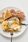 Fried egg, bacon, sausage and toast on plate