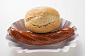 Sausage (bratwurst) and baguette roll in paper dish