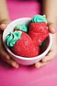 Child's hands holding small bowl of sugar strawberries