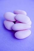 Pink sugared almonds on purple background