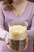 Woman holding plastic tubs of white & dark chocolate chips