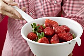 Frau hält Seiher mit Erdbeeren