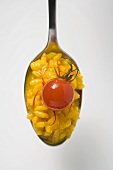 A spoonful of saffron risotto with cherry tomato (overhead)