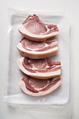 Four raw pork chops on paper