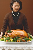 Woman holding stuffed roast turkey on large platter