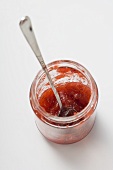 Jam jar with spoon and remains of strawberry jam