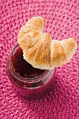 Croissant on a jar of raspberry jam (overhead view)