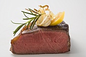Beef steak, showing cut edge, with garlic, rosemary, lemon