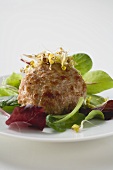 Meat patty with sprouts on salad leaves