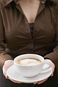 Woman holding large cup of cappuccino