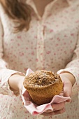 Woman holding muffin on checked napkin