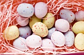 Pastel-coloured sugar eggs in pink Easter grass