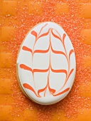 Egg-shaped Easter biscuit on orange background
