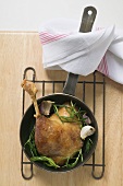 Fried goose leg with rosemary in frying pan (overhead view)