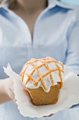 Woman holding iced orange cake on napkin
